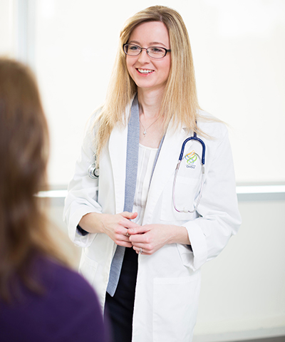 Dr. Elena Varlamov in a lab coat  talking to a patient
