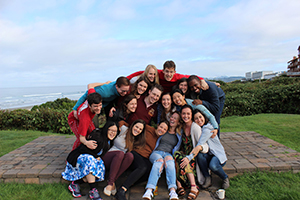 A group of people hugging each other, with the ocean in the background.