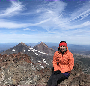 A woman sitting at the peak of a mountain.