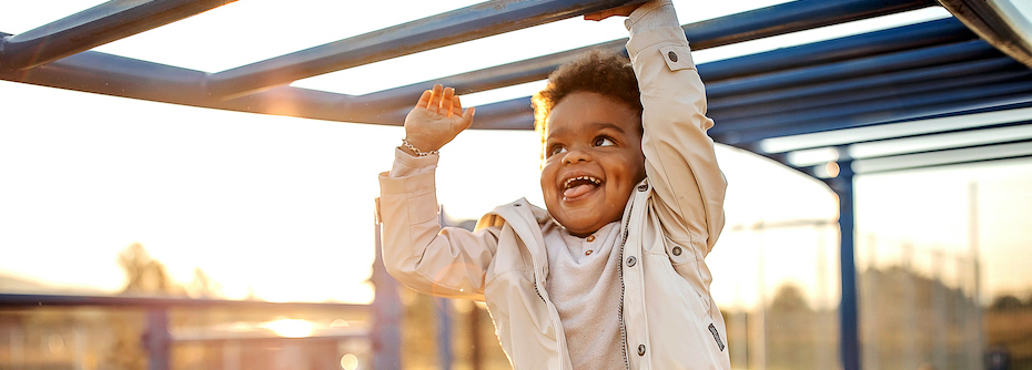 Photo of a smiling child playing on playground equipment