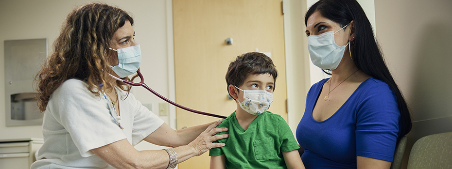 Lisa Crupi listens to a patient’s heartbeat while talking with his mom.