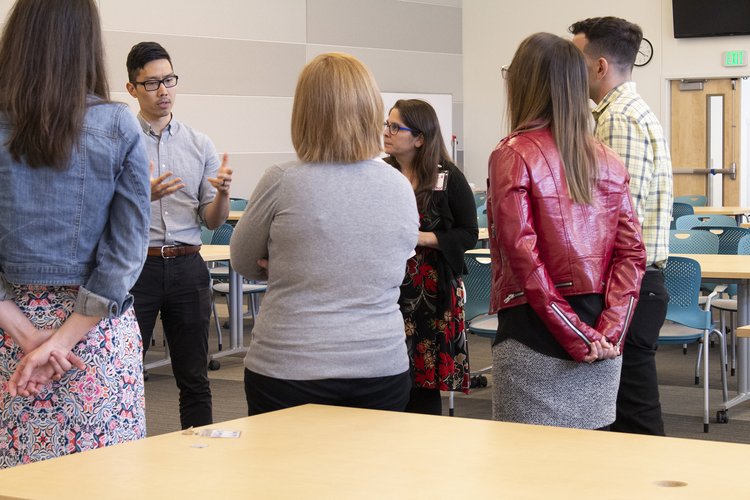 Group stands in a huddle in a classroom engaging in conversation