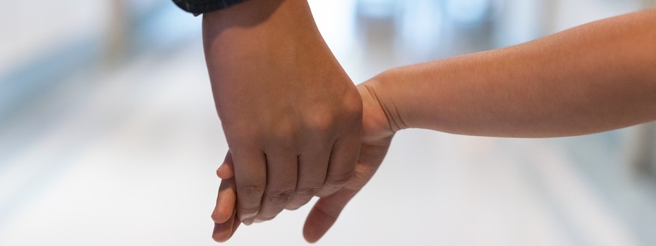 An adult and child walk hand in hand.