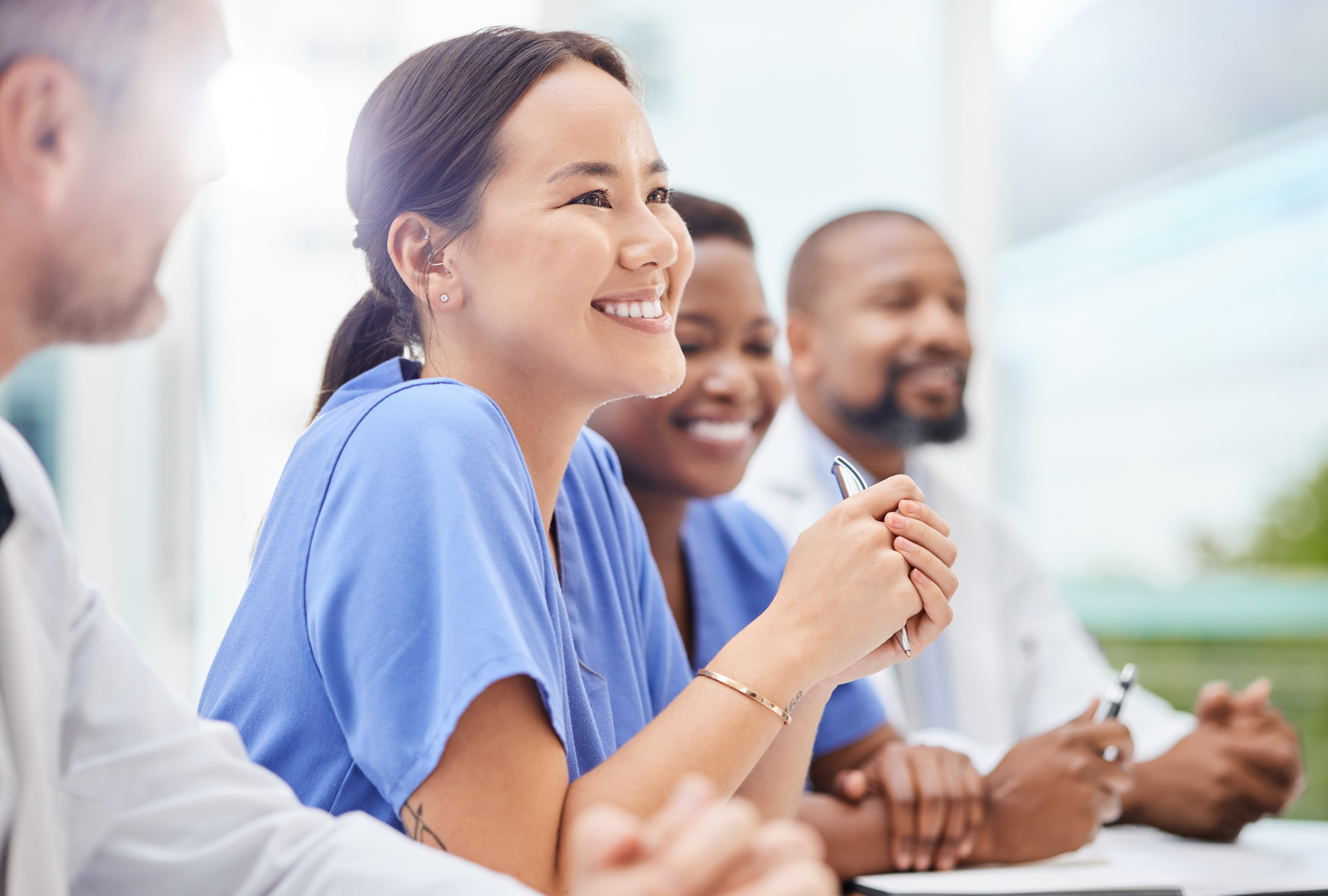 Four smiling health care professionals sitting in a meeting.