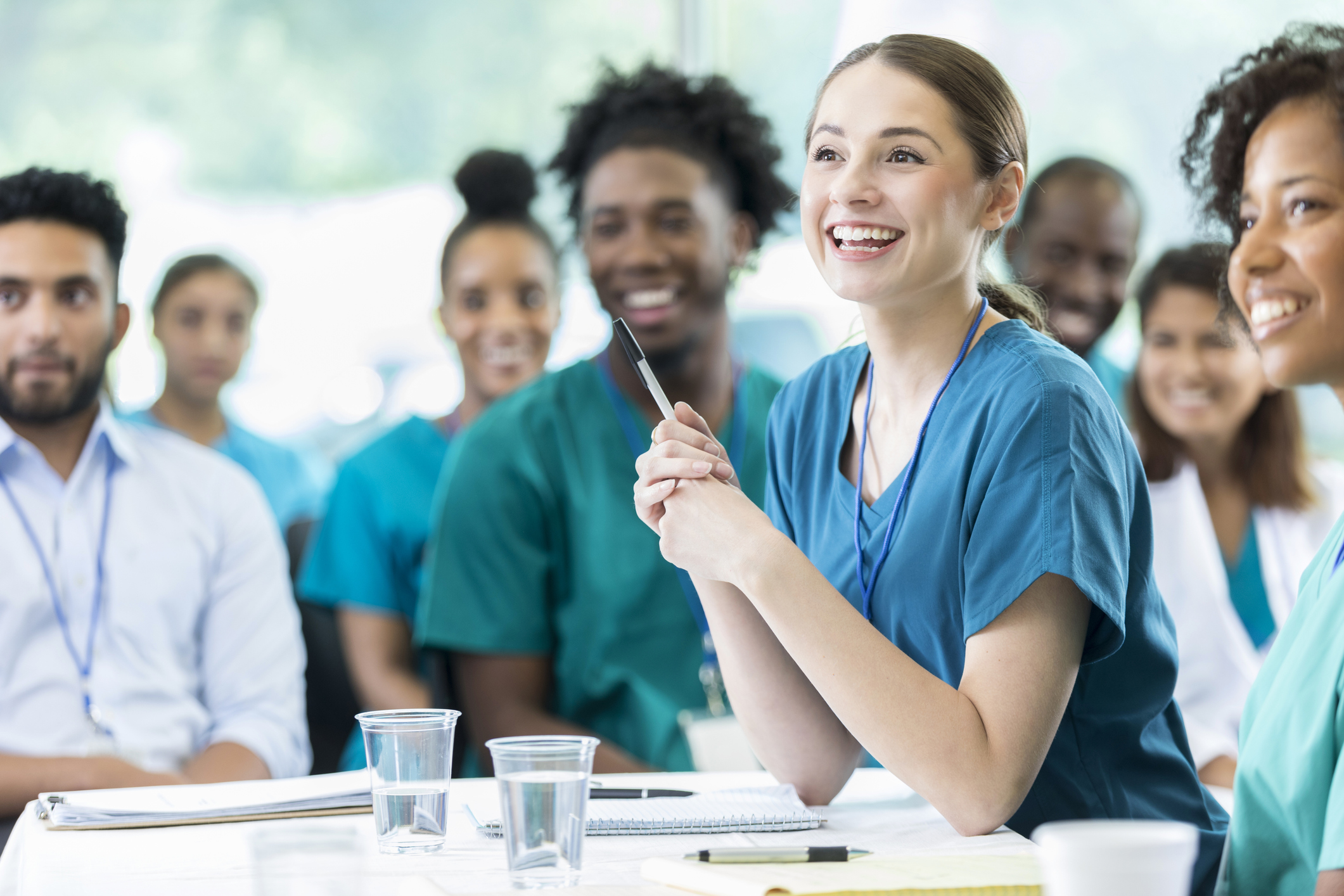A group of health care workers smile as they listen to a training.