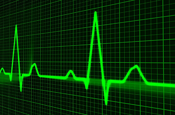 A glowing green line shows the peaks and valleys of a electronically traced pulse line against a back and green grid.