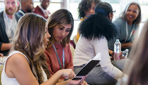 People seated at a conference looking at materials