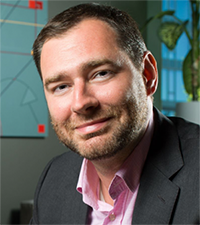 Erik Tucker wears a buttoned shirt and jacket.