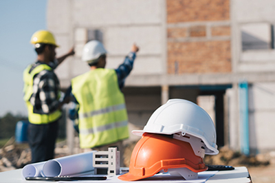 Structural engineer and architect working with blueprints discuss at the outdoors construction site.