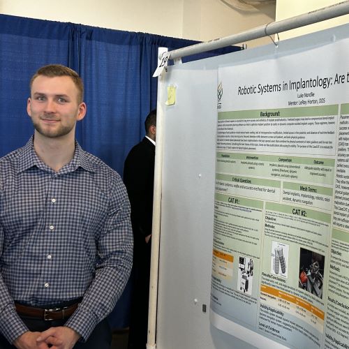 Student standing beside his poster.