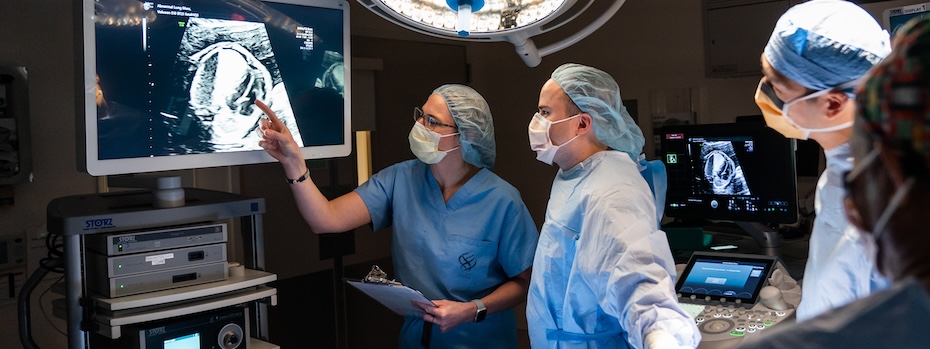 Staff from OHSU’s Fetal Care Program look at an ultrasound on a large monitor in an operating room.