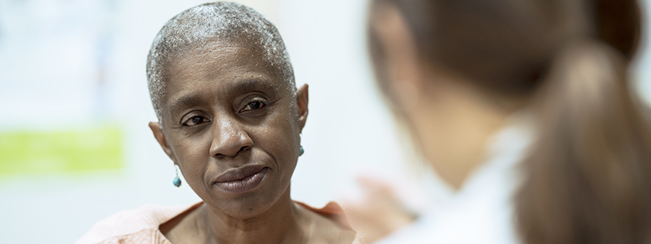 An older Black patient listens to a health care provider.
