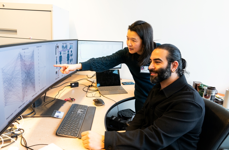 Dr. Ali Karimi and Dr. Aiyin Chen discuss data while looking a results on a computer. 