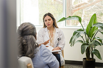 A psychiatric mental health nurse practitioner student listens to a patient in a clinic.