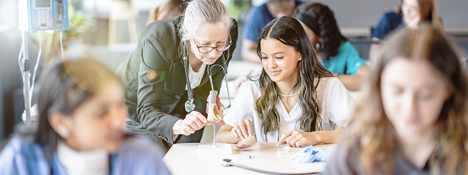 Faculty member teaching student in a health sciences classroom.
