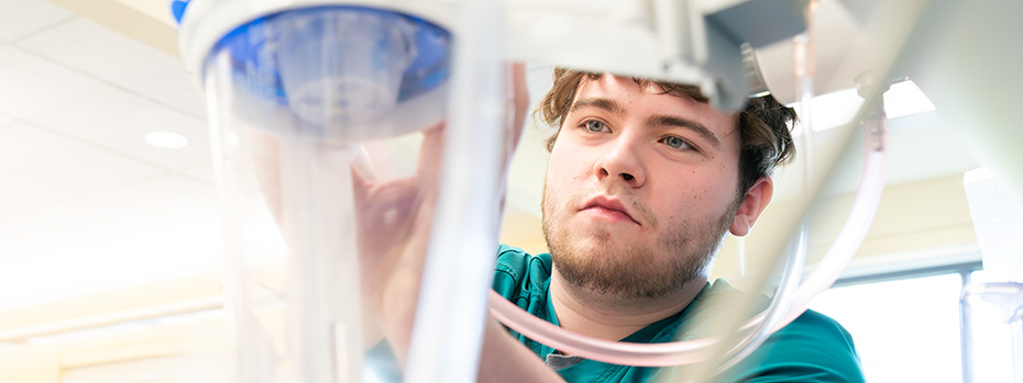 OHSU School of Nursing B.S. in nursing student adjusting medical equipment in a clinical skills lab.