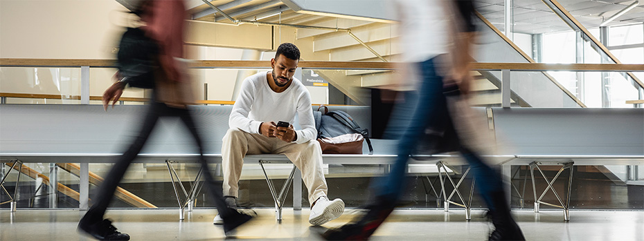 An OHSU student sits on a bench while looking at their phone.