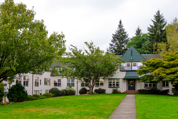 White building with a green awning surrounded with trees