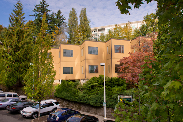 Office building behind a parking lot surrounded by trees