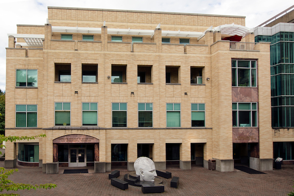 Brick building with a light gray head sculpture in front of it